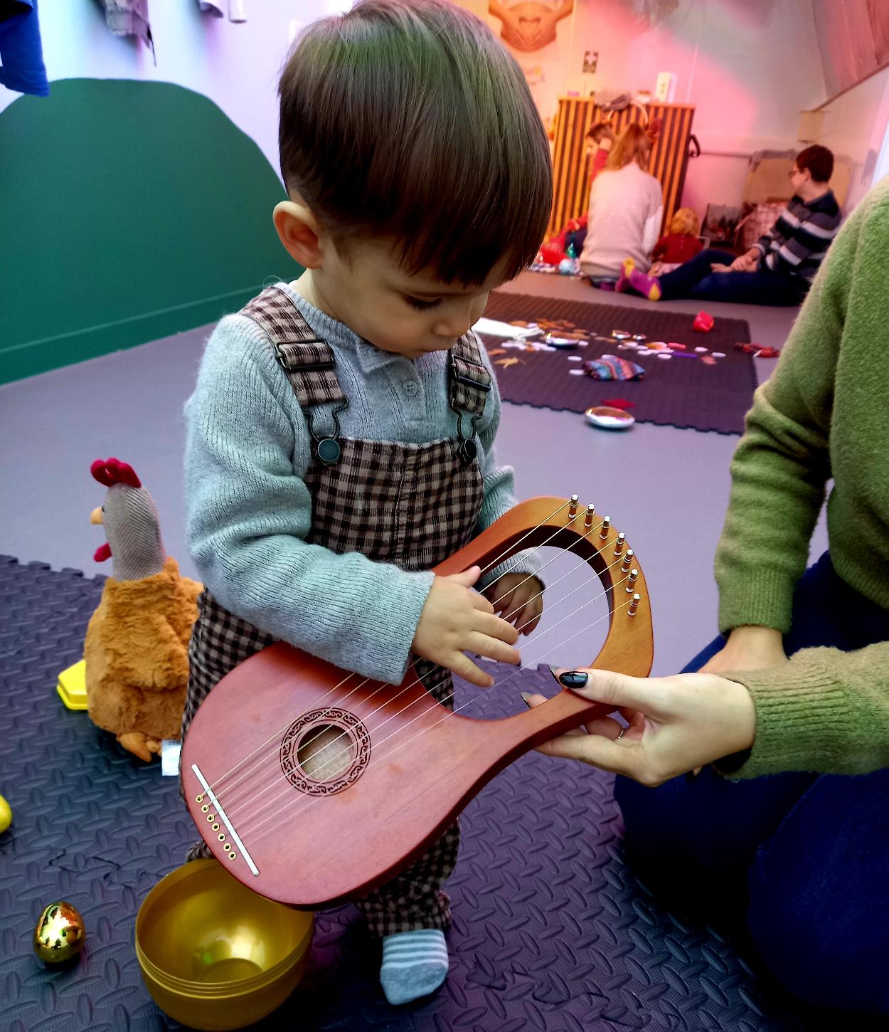 A toddler plays a harp.